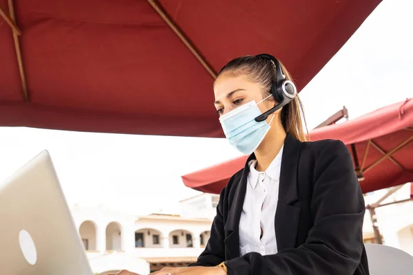 인터넷 프리랜서 헤드폰을 귀여운 여성이 의료용 마스크를 노트북으로 — 스톡 사진
