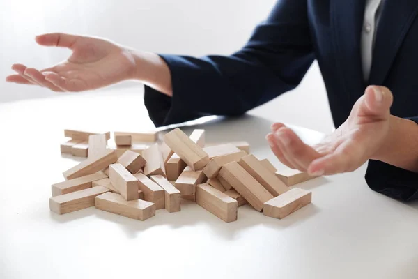 Closeup of business women playing wood blocks stack game, concept of business growth, gambling, risk, bankrupt.