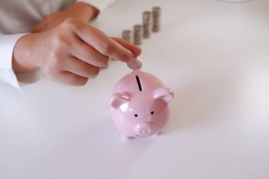 Sikke para yığını ile Piggy banka masanın üzerinde ekleyerek işadamı 