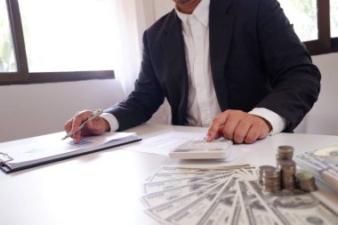 Masanın üzerinde para ve para ile hesap makinesini kullanarak iş adamı.