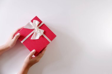 Yakın çekim kadın gönderen kırmızı hediye kutusu beyaz arka plan üzerinde beyaz kurdele ile eller
