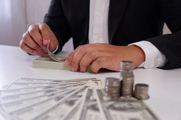 Businessman counting money with coins and money over the desk.