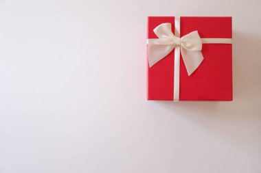 Yakın çekim kırmızı hediye kutusu beyaz arka plan üzerinde beyaz kurdele ile.