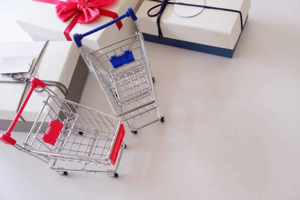 Close-up of gift boxes and shopping cart  on white desk.