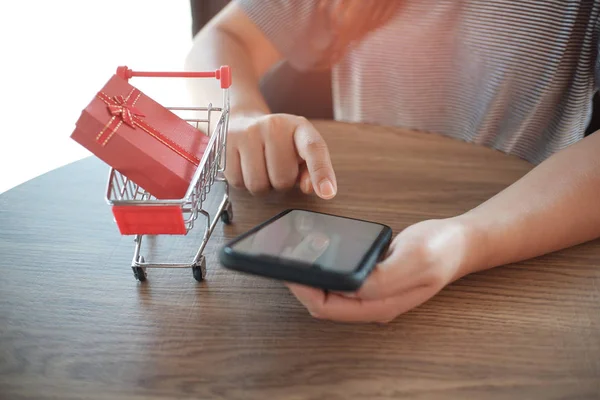 Caixa de presente vermelho no carrinho de compras com mulheres usando telefone móvel. para o conceito de compras online — Fotografia de Stock