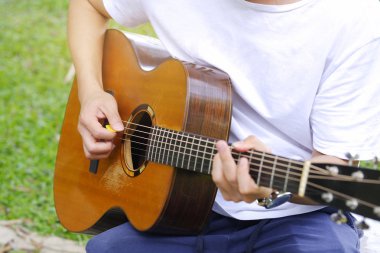 genç adam bahçede akustik gitar çalmak.