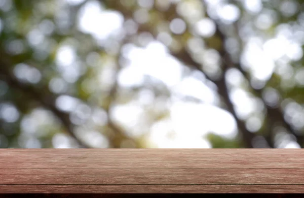 Пустой деревянный стол перед абстрактным размытым зеленым садом и деревьями — стоковое фото