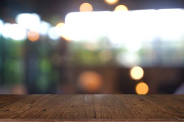 Soyut bulanık kafenin önündeki boş ahşap masa, geceleri restoran. Montaj ürünü görüntüleme veya tasarım için anahtar görsel düzeni - Resim