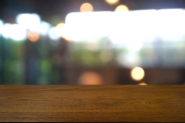 Soyut bulanık kafenin önündeki boş ahşap masa, geceleri restoran. Montaj ürünü görüntüleme veya tasarım için anahtar görsel düzeni - Resim