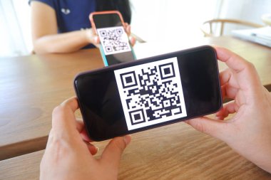 Kadınların eli QR kodlarını taramak için cep telefonu uygulaması kullanıyor. Mağazalarda para ve plastik etiketler olmadan dijital ödeme kabul ediyorlar. QR kod ödemesi ve nakitsiz teknoloji konsepti .