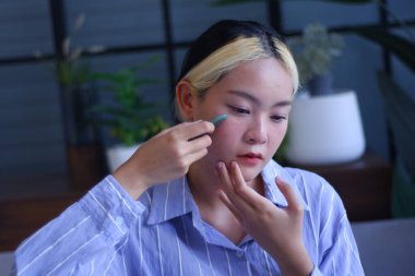 Young Asian women massage her face with Gua-Sha therapy to promoteblood circulation and lymphatic drainage to relieve tension, pain and inflammation, and improve health beauty.