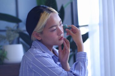 Young Asian women massage her face with Gua-Sha therapy to promoteblood circulation and lymphatic drainage to relieve tension, pain and inflammation, and improve health beauty.