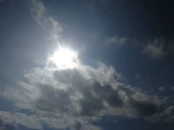 Solen p en bl him mel som lyser frn bakom ett moln 
