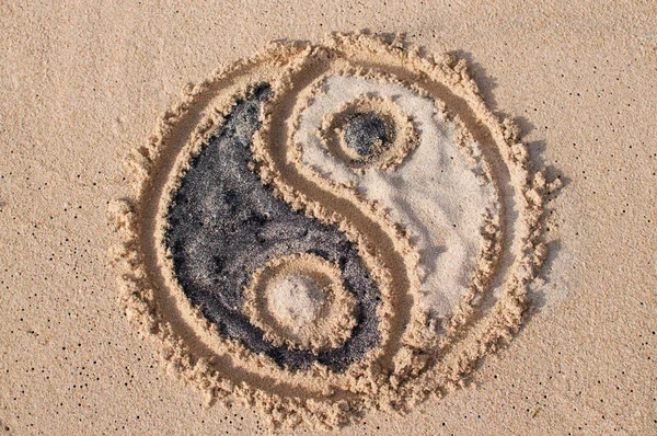 Yin-yang symbol drawn and filled with black and white sand at Melasti beach in Bali, Indonesia