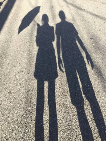 Silhouet van een vrouw die een paraplu en een man staande naast haar — Stockfoto