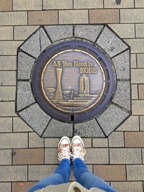 Kobe City, Japonya tipik dekore Manhole önünde ayakta ayakkabı giyen kadın ayaklar