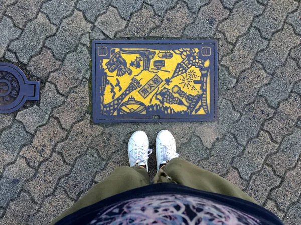 Ženské nohy stojící před žlutou barvou Manhole v Kobe City, Japonsko — Stock fotografie
