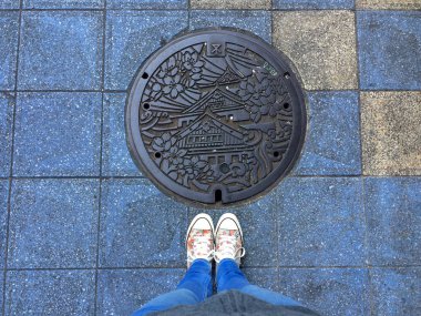 Osaka'da süslenmiş bir rögarın önünde duran kadın bacakları