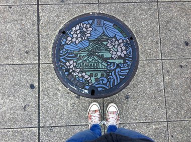Osaka'da süslenmiş bir rögarın önünde duran kadın bacakları