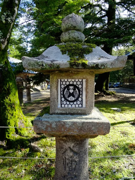 Lanterna de pedra com o logotipo de dois pássaros apaixonados no templo Tamukeyama Hachimangu em Nara, Japão — Fotografia de Stock