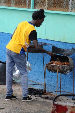 Jamaican man is cooking Jerk chicken clipart