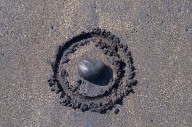 Siyah kum üzerine çizilmiş bir daire içinde döşenmiş siyah taş