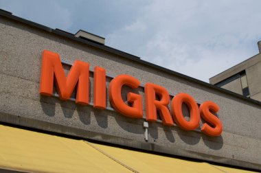 Lugano, Ticino, İsviçre - 3 Haziran 2020: Lugano 'da bir mağazanın önünde asılı duran Migros süpermarket logosu. Migros şirketi İsviçre 'nin en büyük perakende ve toptan satış şirketidir.