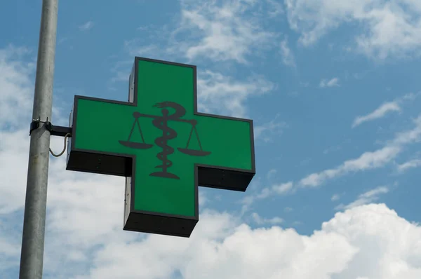 A generic Pharmacy logo against a blue sky in Lugano, Switzerland