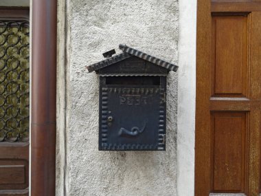 Eski metal posta kutusu iki farklı kapı arasındaki bir taşın üzerinde.