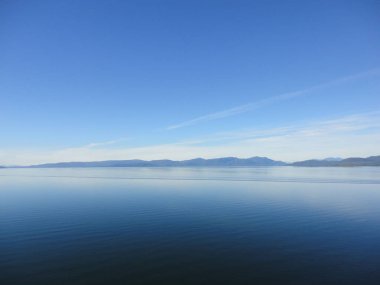 Kıyı boyunca iç görünümünü Alaska pasajda. Parlak mavi gökyüzü ve kapalı ufuk içine uzanan su. Huzur içinde sakin okyanus.