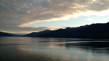 Pasifik Okyanusu 'nda dağ dolu ufukta. Kısmen bulutlu gökyüzü ile geçiş Alaska günbatımı içinde güzel renkler