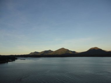 Pasifik Okyanusu 'nda dağ dolu ufukta. Gün batımı ve tepeler arasındaki boşlukları dolduran renkli bir gökyüzü içinde Alaska geçiş