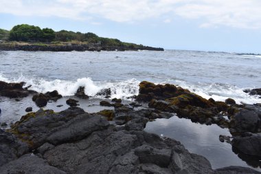 Dalgalar mavi bir gökyüzü altında kayalar üzerinde yıkamak gibi Hawaii beyaz köpük Rocky Shore üzerinde çökmesini dalgalar