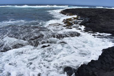 Dalgalar mavi bir gökyüzü altında kayalar üzerinde yıkamak gibi Hawaii beyaz köpük Rocky Shore üzerinde çökmesini dalgalar
