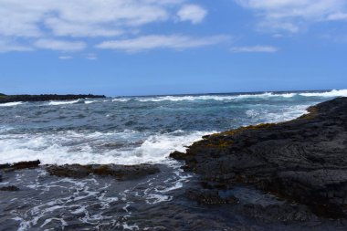 Dalgalar mavi bir gökyüzü altında kayalar üzerinde yıkamak gibi Hawaii beyaz köpük Rocky Shore üzerinde çökmesini dalgalar