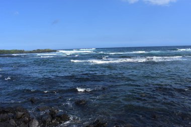 Dalgalar mavi bir gökyüzü altında kayalar üzerinde yıkamak gibi Hawaii beyaz köpük Rocky Shore üzerinde çökmesini dalgalar
