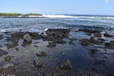 Dalgalar mavi bir gökyüzü altında kayalar üzerinde yıkamak gibi Hawaii beyaz köpük Rocky Shore üzerinde çökmesini dalgalar