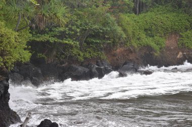 Dalgalar mavi bir gökyüzü altında kayalar üzerinde yıkamak gibi Hawaii beyaz köpük Rocky Shore üzerinde çökmesini dalgalar
