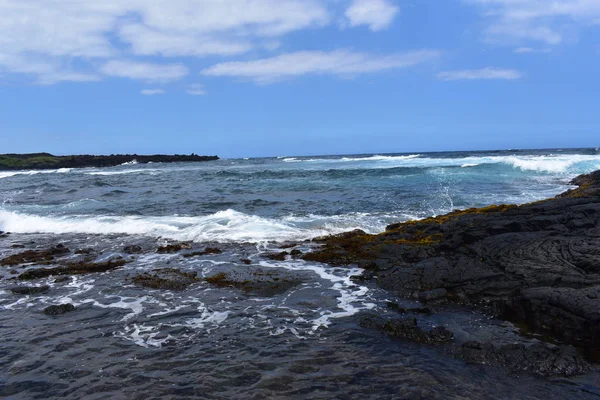 Dalgalar mavi bir gökyüzü altında kayalar üzerinde yıkamak gibi Hawaii beyaz köpük Rocky Shore üzerinde çökmesini dalgalar