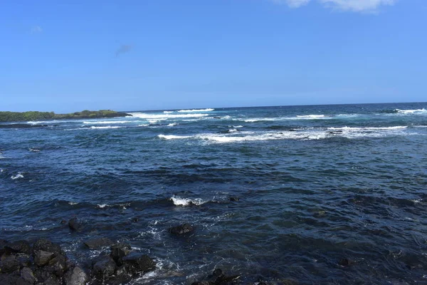 Dalgalar mavi bir gökyüzü altında kayalar üzerinde yıkamak gibi Hawaii beyaz köpük Rocky Shore üzerinde çökmesini dalgalar