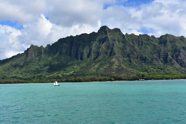 View of Mountains from the Ocean with clouds under a blue sky