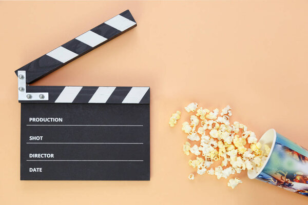 black clapperboard and popcorn with free space for text isolated on color background