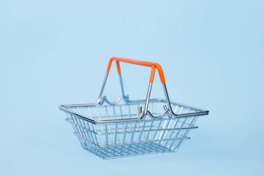 Mavi arka plan üzerinde tekerlekler üzerinde boş bakkal arabası