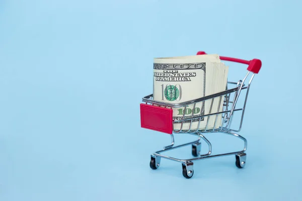 Einkaufswagen mit amerikanischen Dollars auf blauem Hintergrund — Stockfoto
