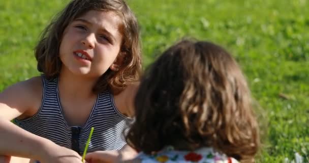 Een meisje praten met B meisje in een tuin — Stockvideo