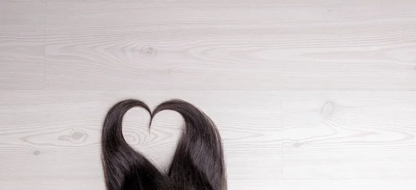 Herzförmiges Haarschloss Aus Langen Haaren Auf Einer Hölzernen Flachen Oberfläche — Stockfoto