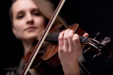 focus on the hand of a baroque violinist player on a black background, she's very serios and determined clipart