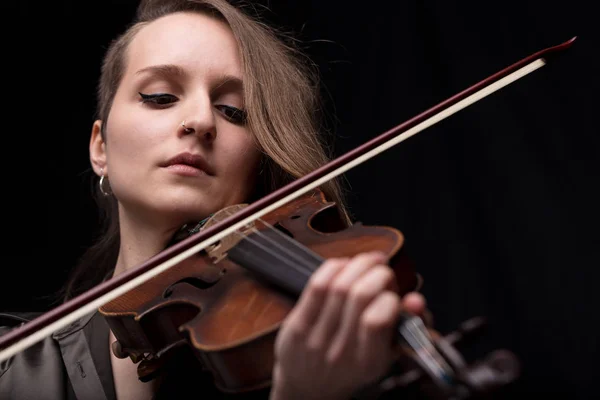 Stock image serious and concentrated violin player - portrait of a woman on black background playing strings