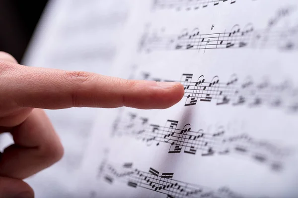 音乐分数与一些音符指出了一个女人的手指发现一些细节 — 图库照片