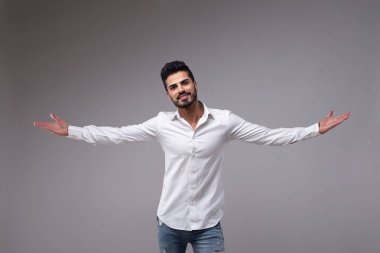Portrait of young bearded man with outstretched arms wearing white shirt clipart